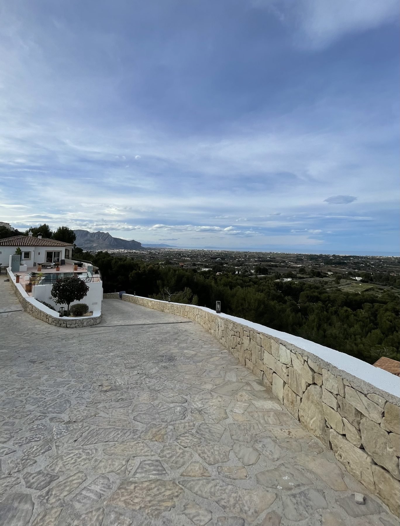 Muro de piedra natural limpia con remate blanco recién pintado y vistas panorámicas a la Marina Alta en La Sella