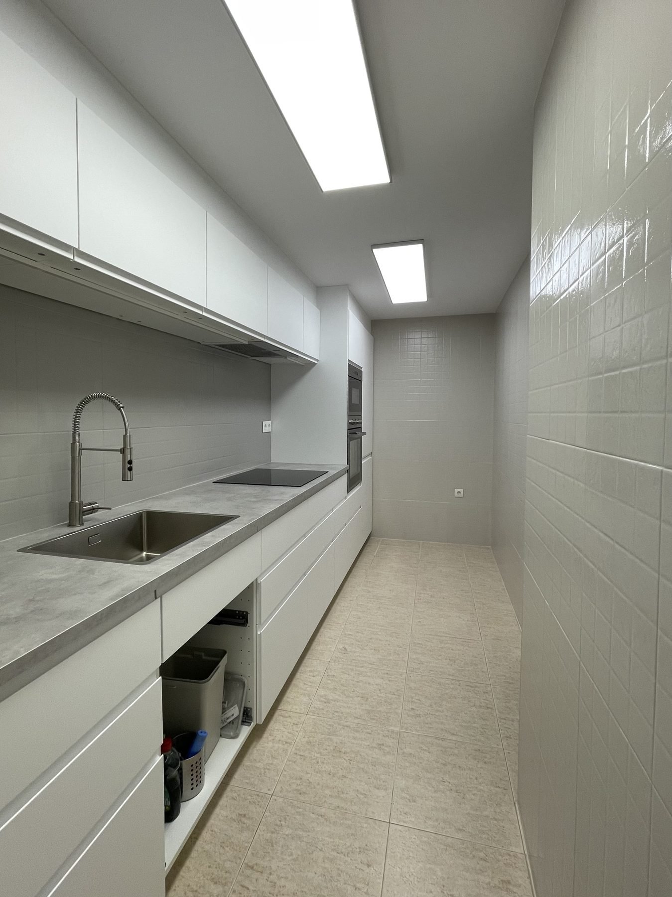 Cocina estrecha renovada con azulejo brillante y suelo nuevo en Dénia