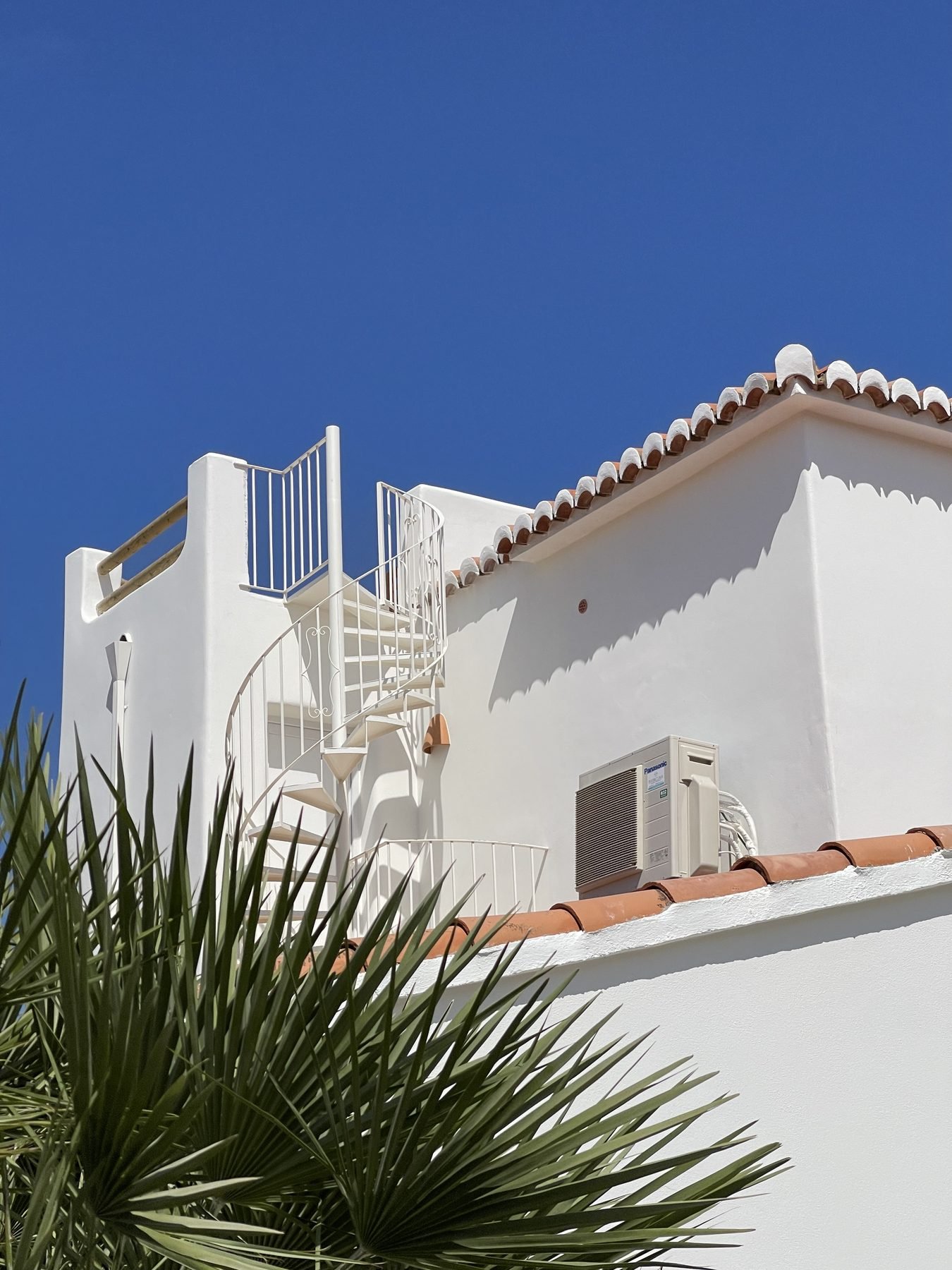Fachada blanca de Villa Mozart con escalera de caracol y tejado de teja en Jávea