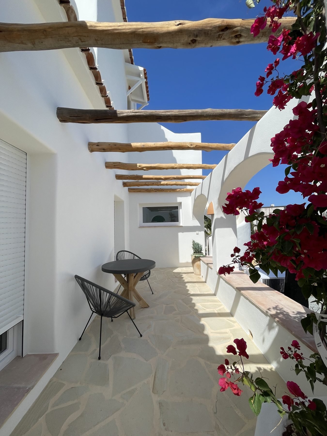Pérgola de madera y muro de piedra recién pintado en la terraza de Villa Mozart, Jávea